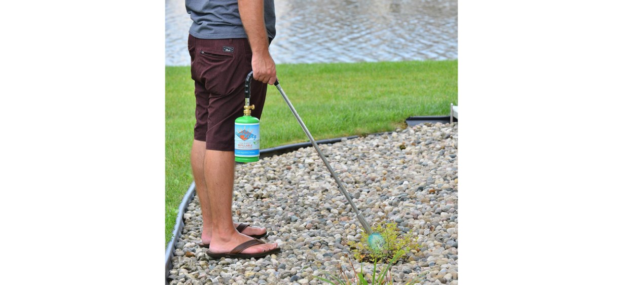 Person using Flame King Propane Torch Weed Burner in rock gardener