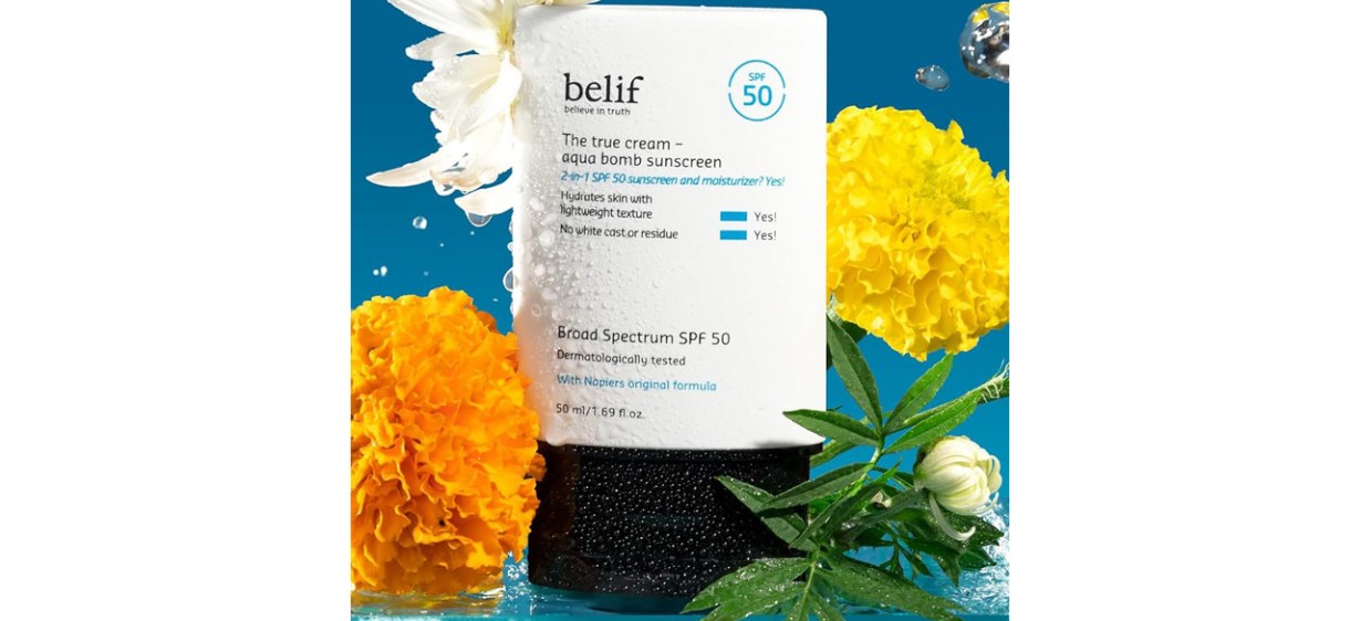 Bottle of Belif The True Cream Aqua Bomb Sunscreen 2-in-1 SPF 50 and Moisturizer on blue background with flowers