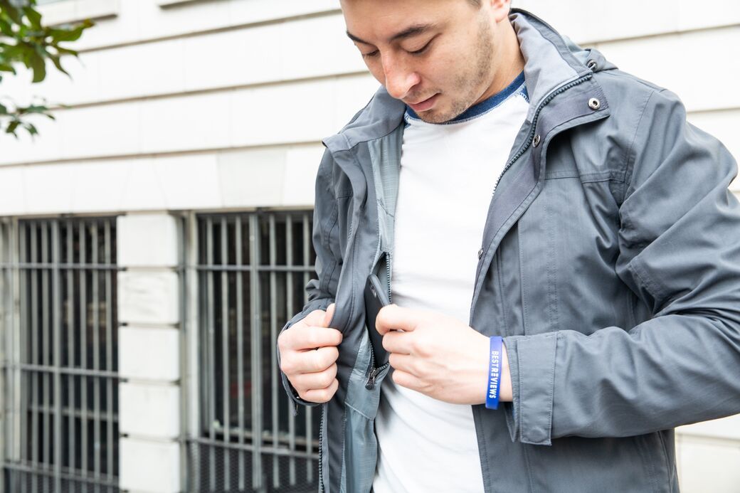 Man placing phone in pocket of rain jacket