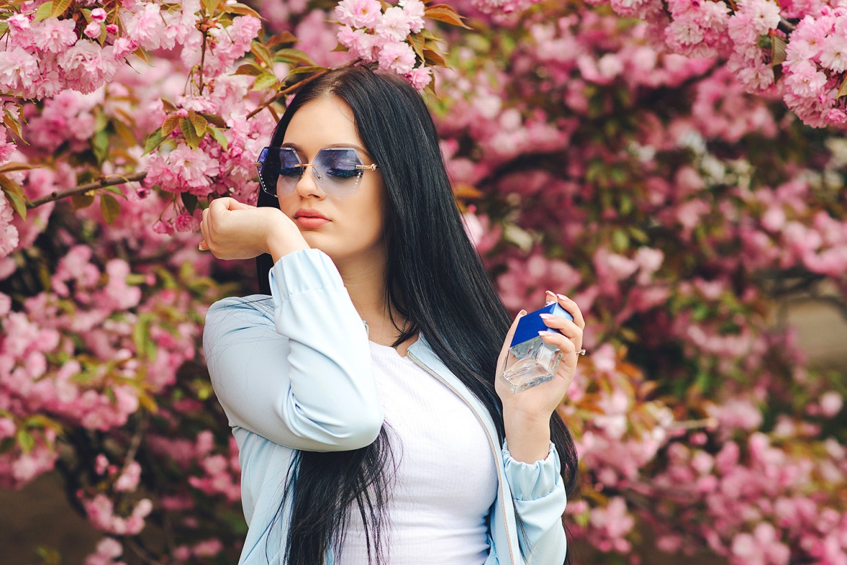 a woman in sunglasses smelling her wrist